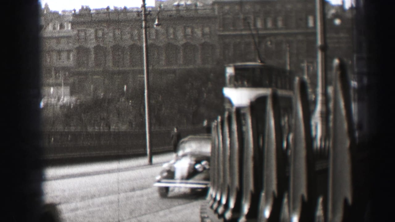A 1952 Edinburgh street scene shows an older car passing near a double-decker trolley, with pedestrians and large buildings in soft focus.