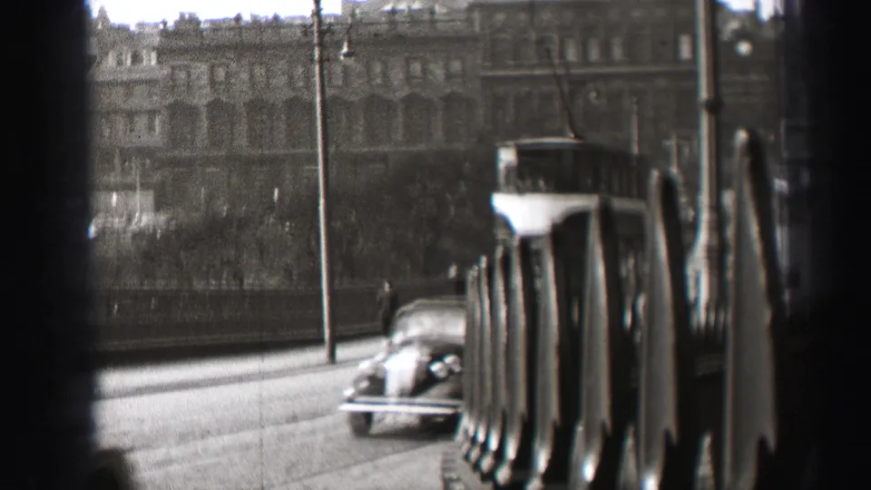 A 1952 Edinburgh street scene shows an older car passing near a double-decker trolley, with pedestrians and large buildings in soft focus.