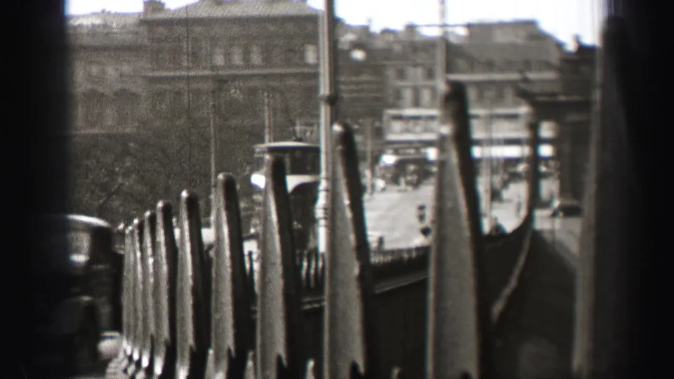 A distant trolley, pedestrians, railings, and multi-story city buildings appear in a soft black-and-white 1952 Edinburgh street view.