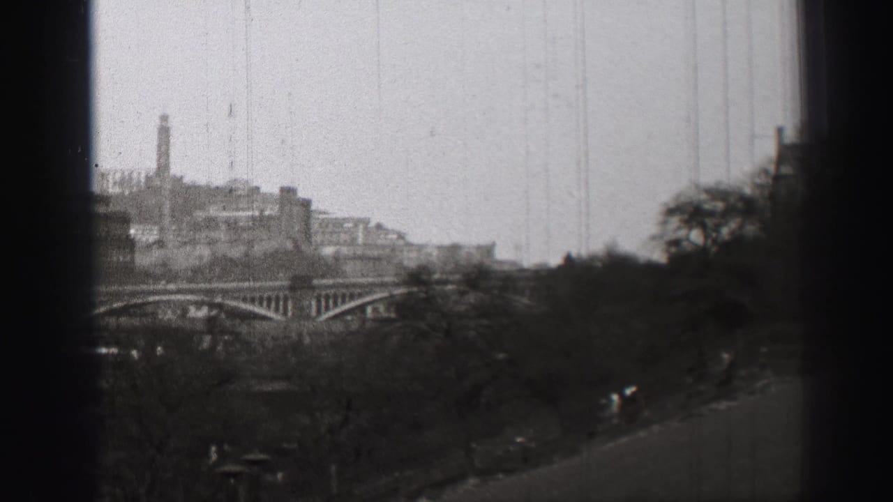 1952 Edinburgh cityscape seen from an elevated viewpoint, with an arched bridge, trees, and dark film-edge obstruction.