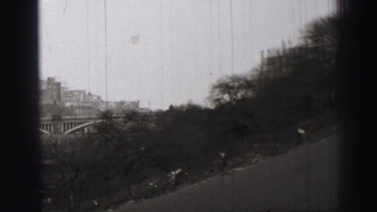 Sloping parkland and distant arched bridge with buildings partly obscured by dark edges.