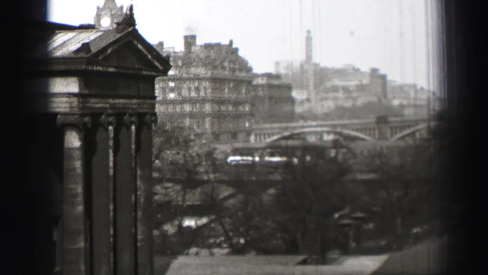 1952 Edinburgh overlook with a columned foreground structure, arched bridge, dense buildings, bare trees, and a tall distant tower.