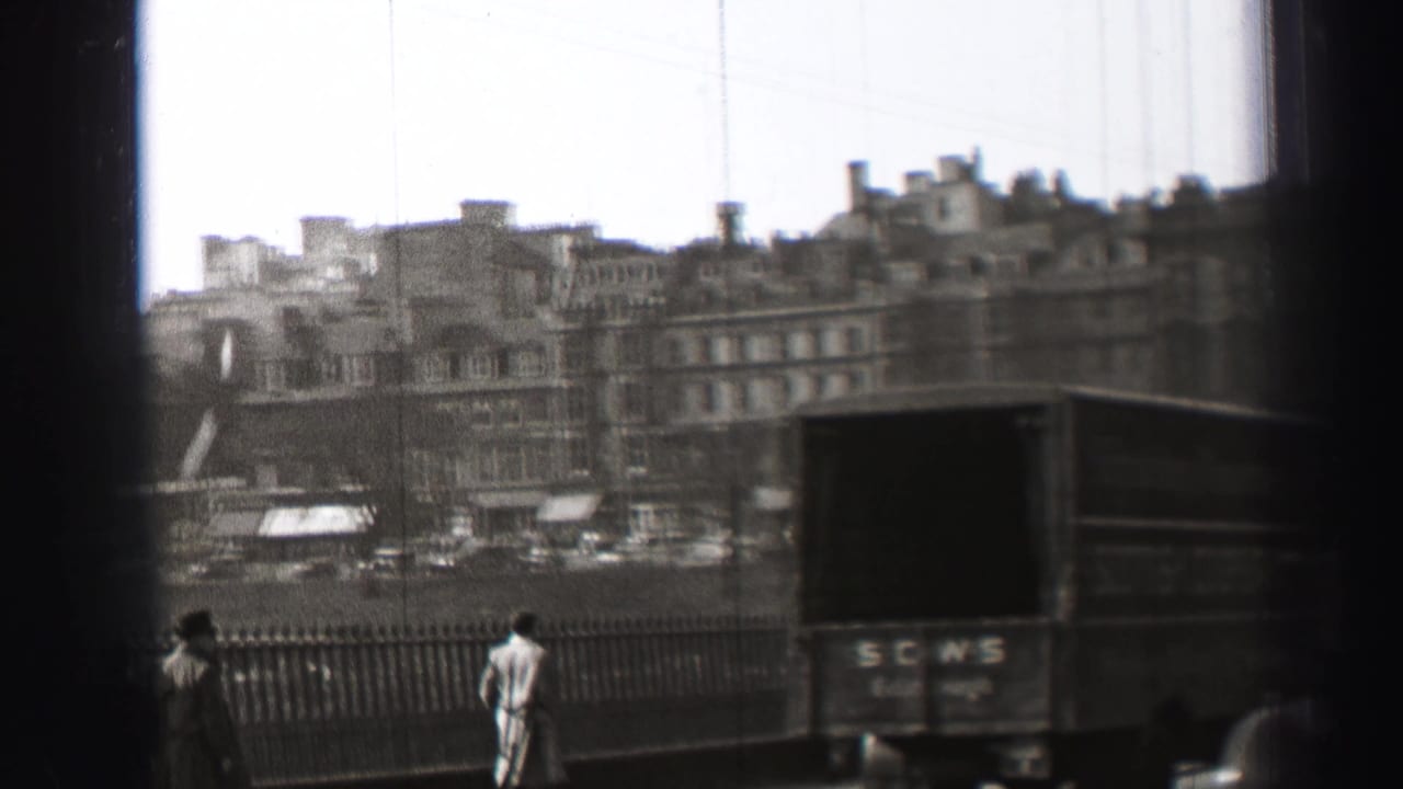 1952 Edinburgh bridge view with pedestrians by the railing, a marked delivery truck, overhead wires, and stone buildings in the distance.