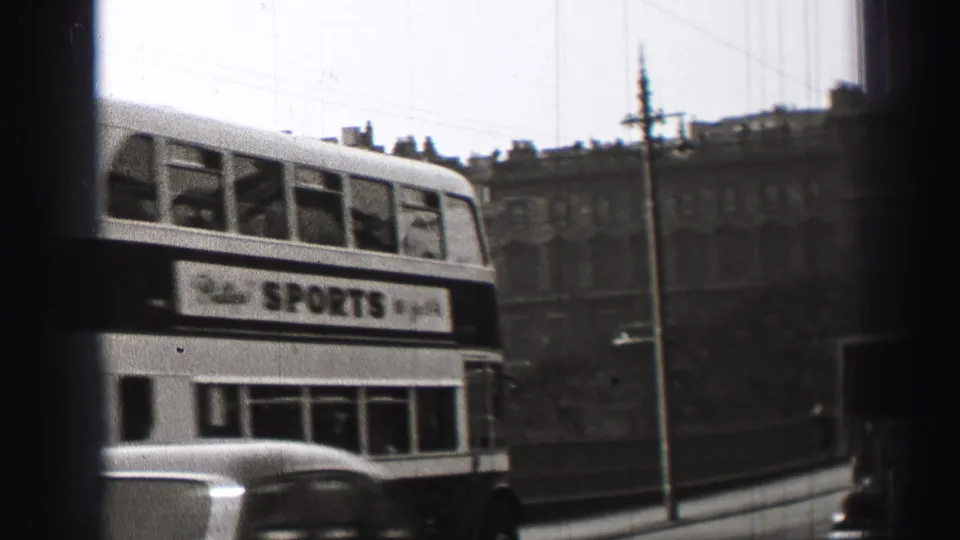 1952 Edinburgh traffic frame showing a double-decker bus with a Sports advertisement, car roof, bridge edge, and stone buildings behind.