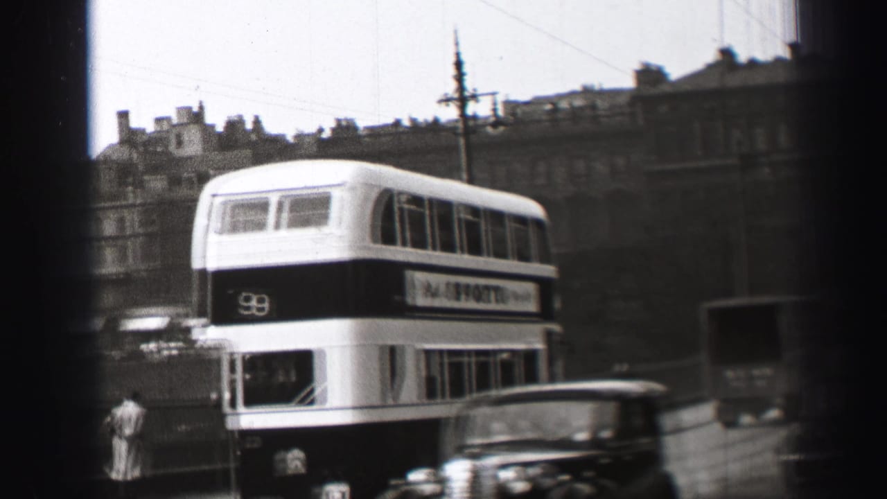 1952 Edinburgh street view with a route 9 double-decker bus, vintage cars, pedestrians, and overhead wires seen through a dark frame.