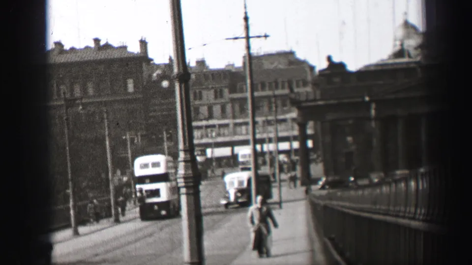1952 Edinburgh street view with a double-decker bus, classic car, pedestrians, railings, poles and overhead wires.