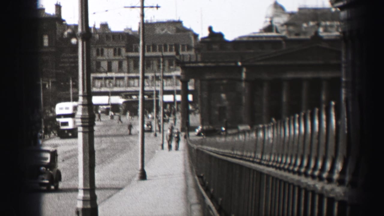 Street view with a double-decker bus, pedestrians, lampposts, railings, and a classical stone structure.