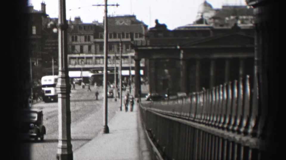 1952 Edinburgh street scene showing a bus, pedestrians, tall lampposts, railings, and formal stone architecture.