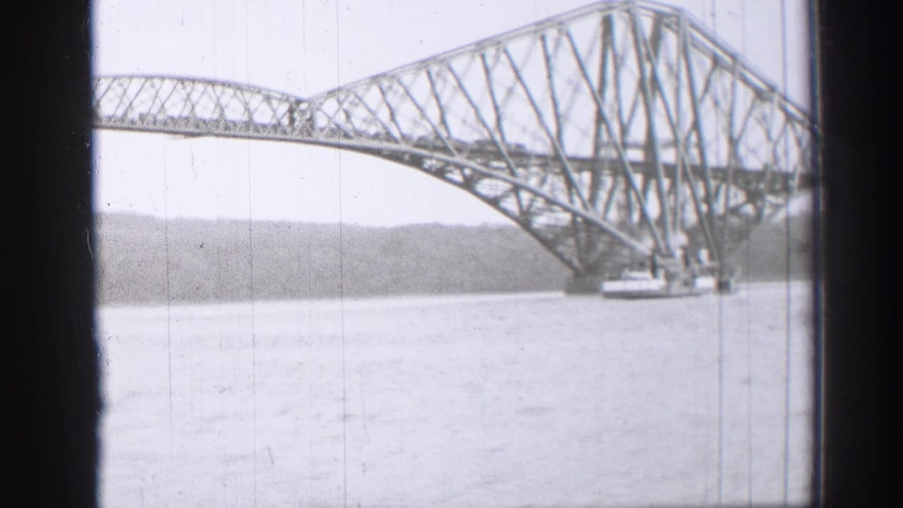 Forth Bridge span over water with distant shore behind it.