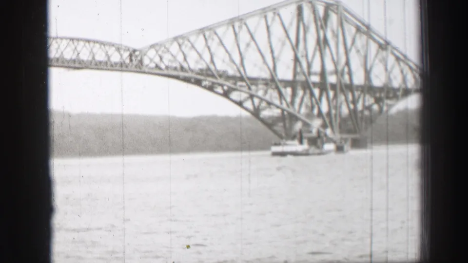 1952 home-movie still of the Forth Bridge over the Firth of Forth, with water and shoreline beneath the cantilever structure.