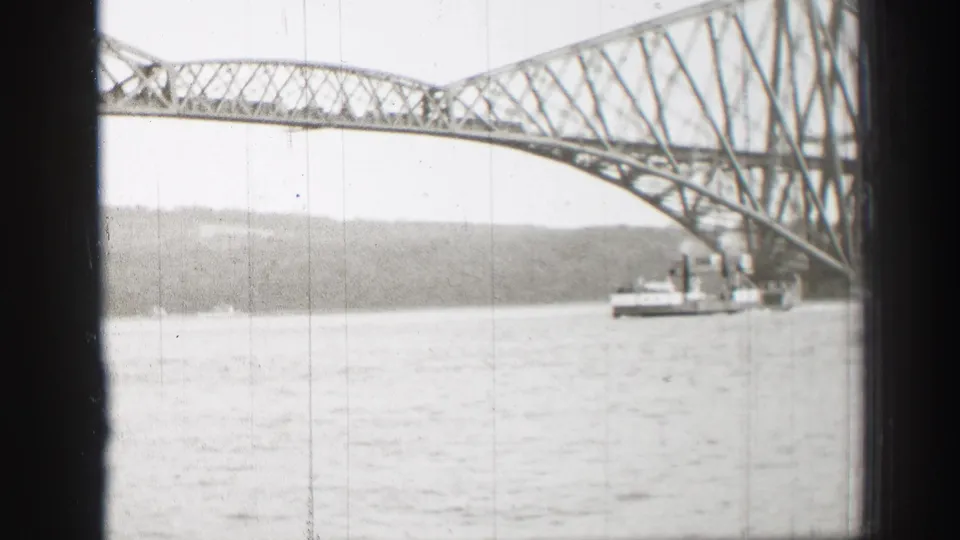 1952 8mm view in Scotland showing a steel truss bridge crossing water, with a steamboat or ferry near the bridge span.