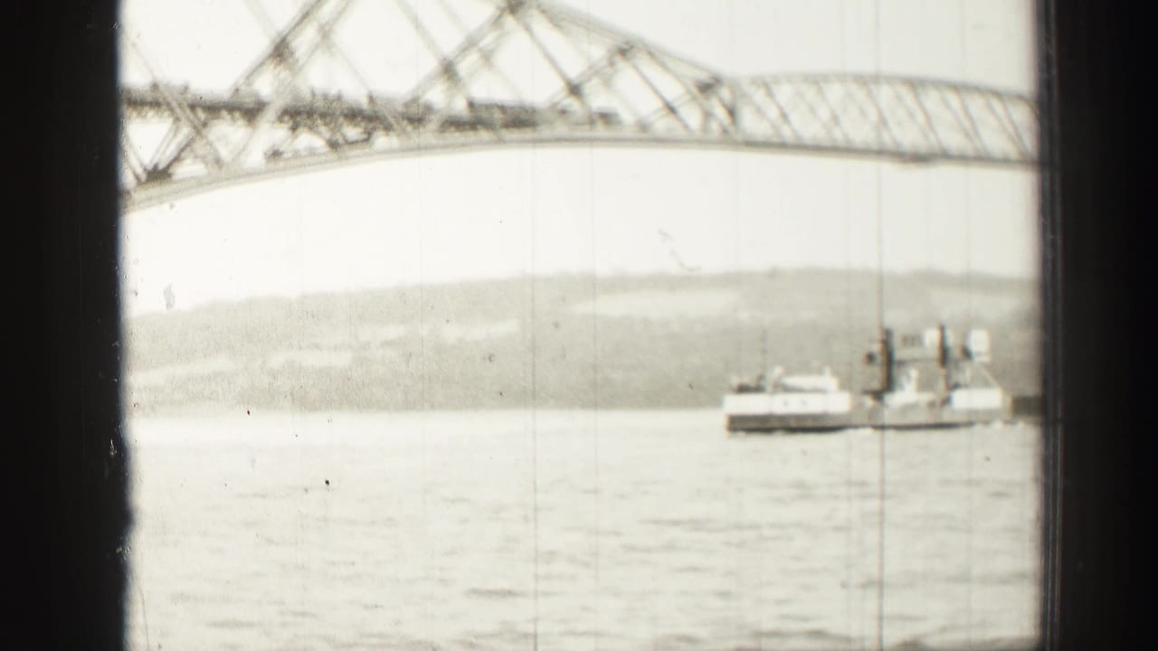 Ferry or workboat on calm water beneath a steel truss bridge.