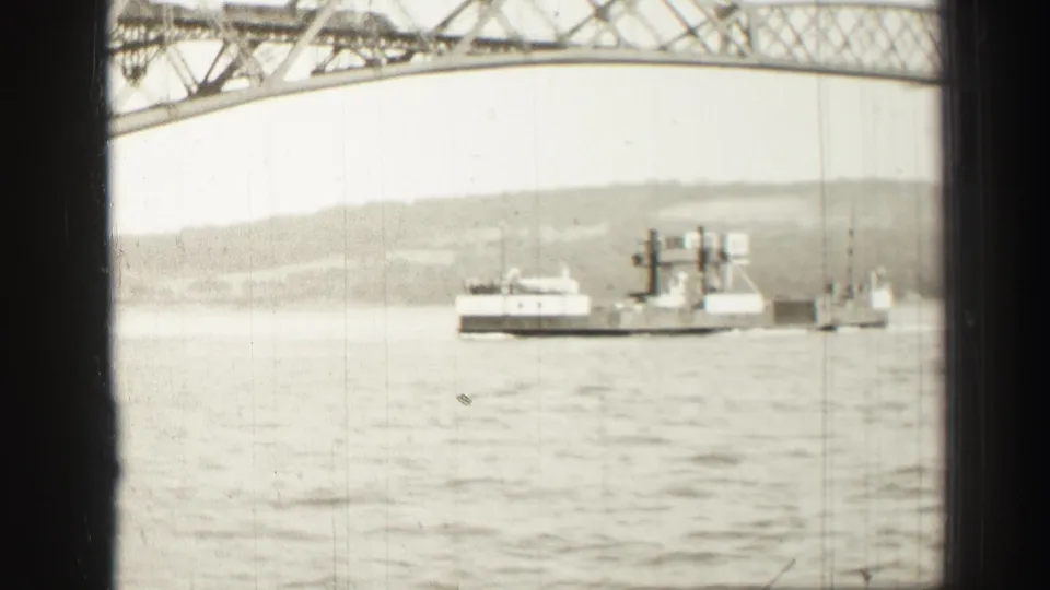 A 1952 Edinburgh-area 8mm view shows a ferry or workboat beside a smaller craft, framed by a steel bridge and distant shoreline.
