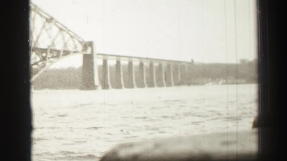 1952 home-movie frame showing the steel bridge stretching over a broad river near Edinburgh, Scotland.