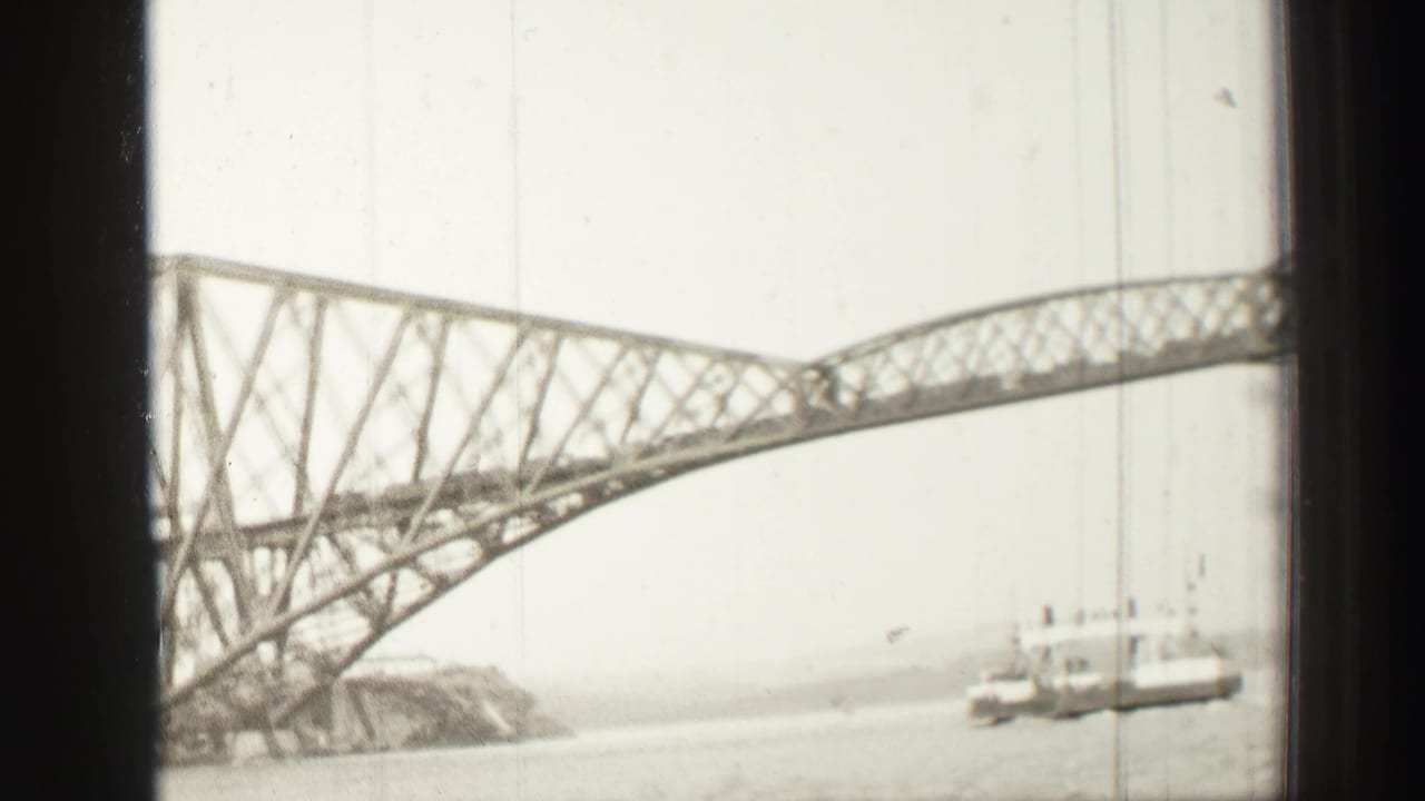 Forth Bridge seen from a boat window with water and a small vessel below.