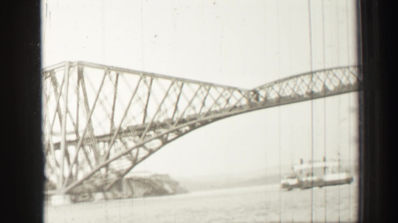 The Forth Bridge appears through dark boat-window bars, showing the steel cantilever structure, water, shoreline, and a small vessel.