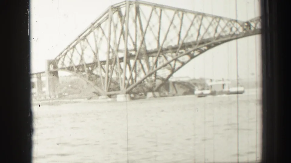 1952 8mm view of the Forth Bridge in Scotland spanning water, with steel trusswork and river surface in the foreground.
