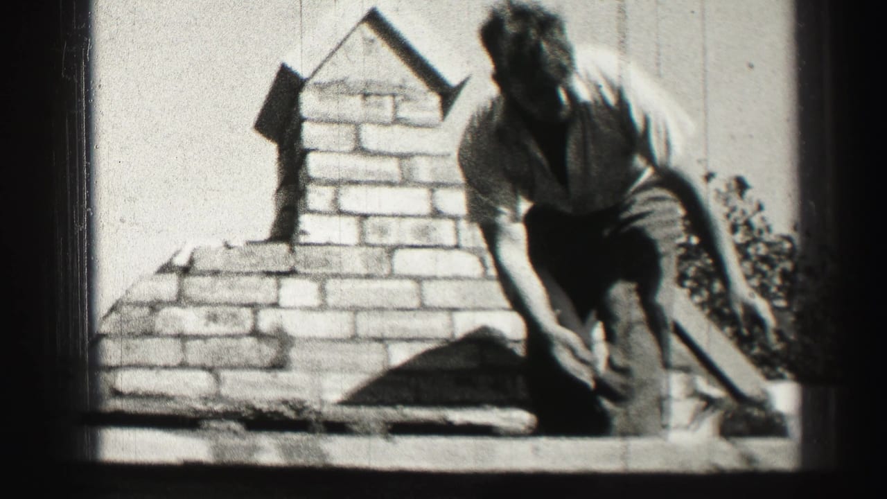 Worker bends near a brick chimney with tools on a rooftop.