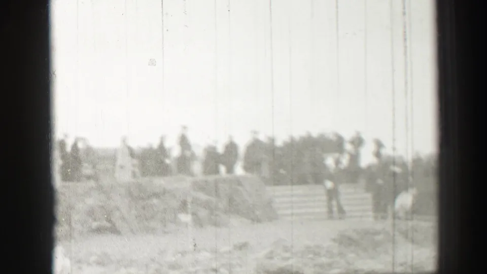 Grainy 1952 Scotland home-movie frame showing people gathered on stone steps near rough stonework.