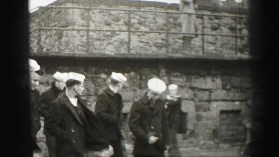 A closer 1952 Edinburgh view shows sailors in dark uniforms walking beneath a raised stone walkway, with rough masonry filling the background.