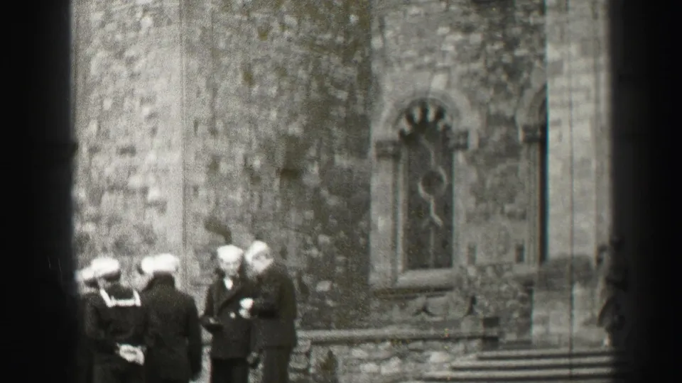 Sailors in white caps pause near stone steps and a gothic-style arched window, with a civilian partly visible at the frame edge.