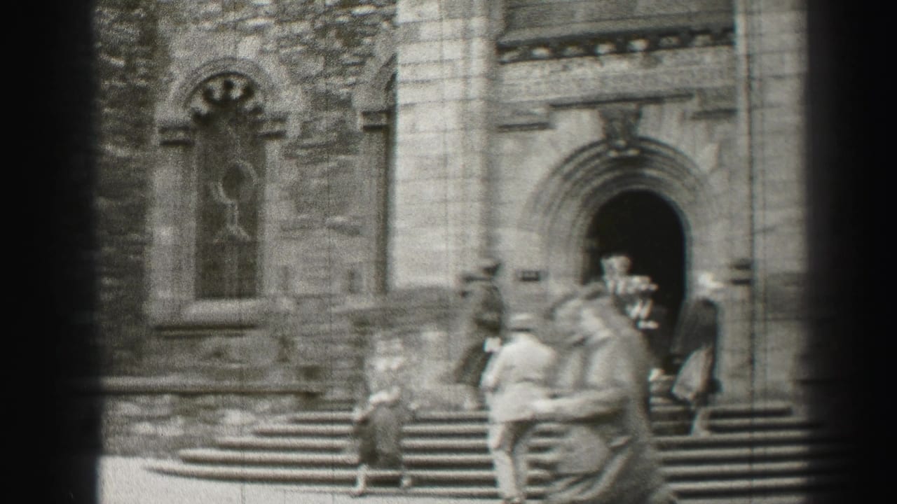 People walk and stand on cathedral steps beside a large arched doorway and stone facade.