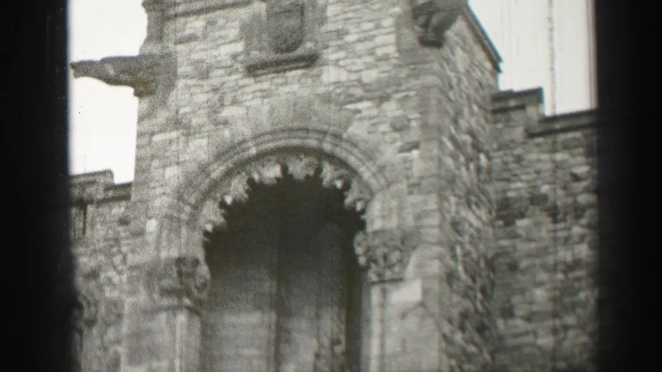 Close exterior view of a stone cathedral doorway in Scotland, with carved arch detail and home-movie softness.