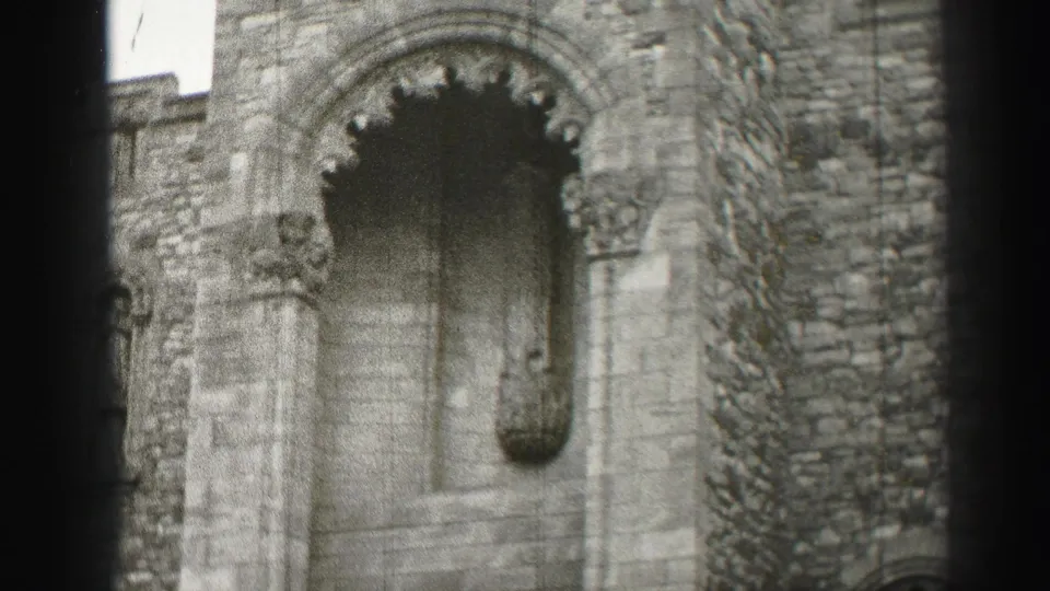 1952 Edinburgh footage frame showing a weathered stone facade with a recessed arch, carved surround, and narrow vertical detail.