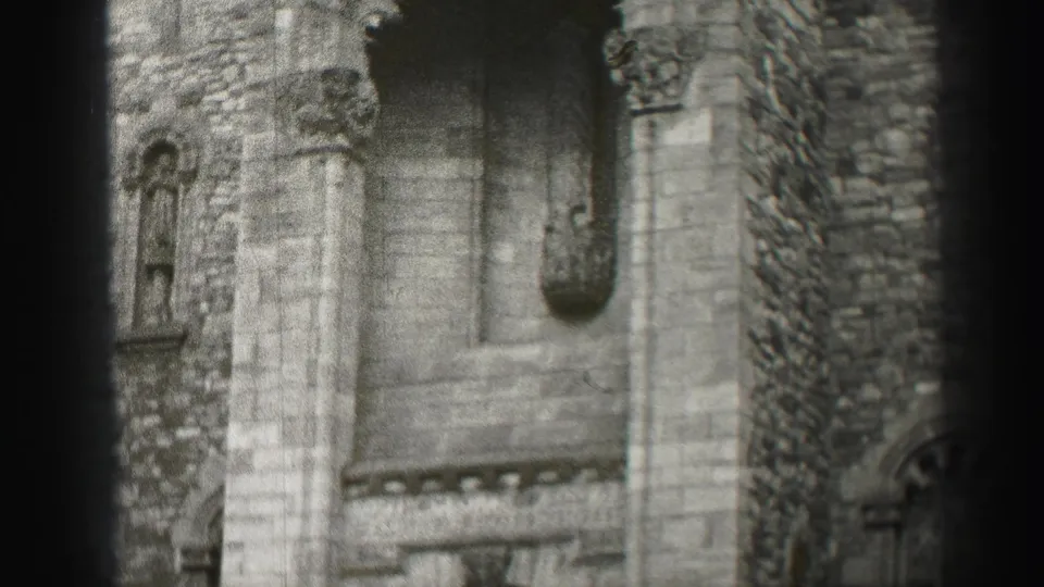1952 Edinburgh home-movie frame showing the lower portion of a stone Romanesque-style facade with columns and a recessed opening.