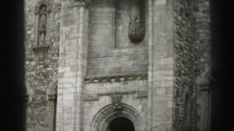 1952 Edinburgh frame showing a stone building facade with an arched lower opening, carved vertical support, and weathered masonry.