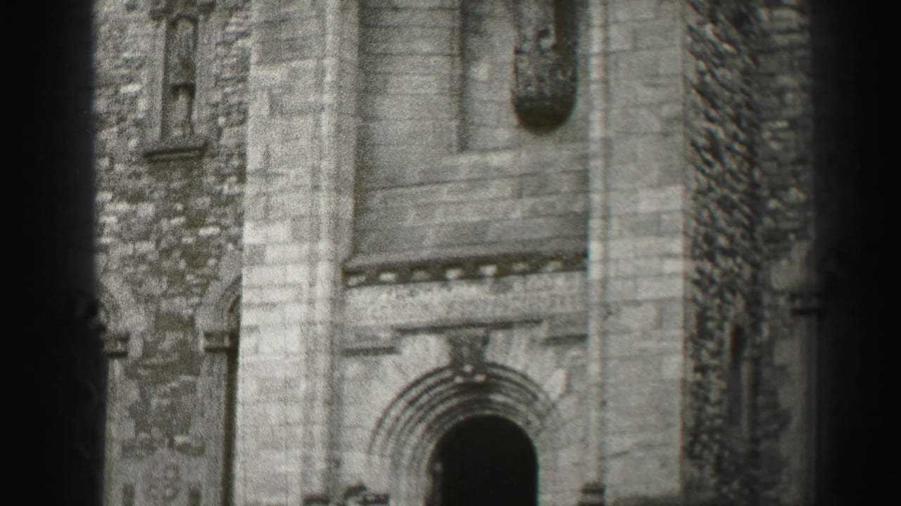 Black-and-white 8mm frame of a historic stone church facade in Edinburgh, with an arched doorway partly obscured by film-edge bands.