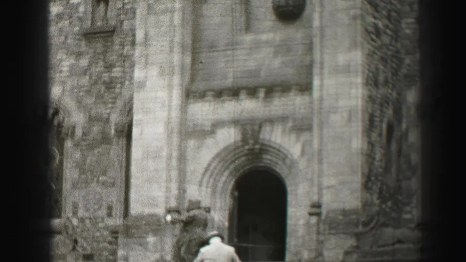 In this 1952 Edinburgh church exterior, a man in a light suit walks up the steps toward a dark arched doorway.