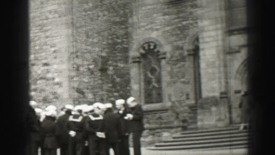 A group of sailors in white caps and dark uniforms stands on stone steps outside a church in 1952 Edinburgh.
