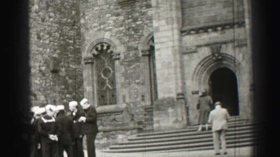 Sailors in white caps stand at the edge of the frame while a suited man pauses near a church doorway in Edinburgh.