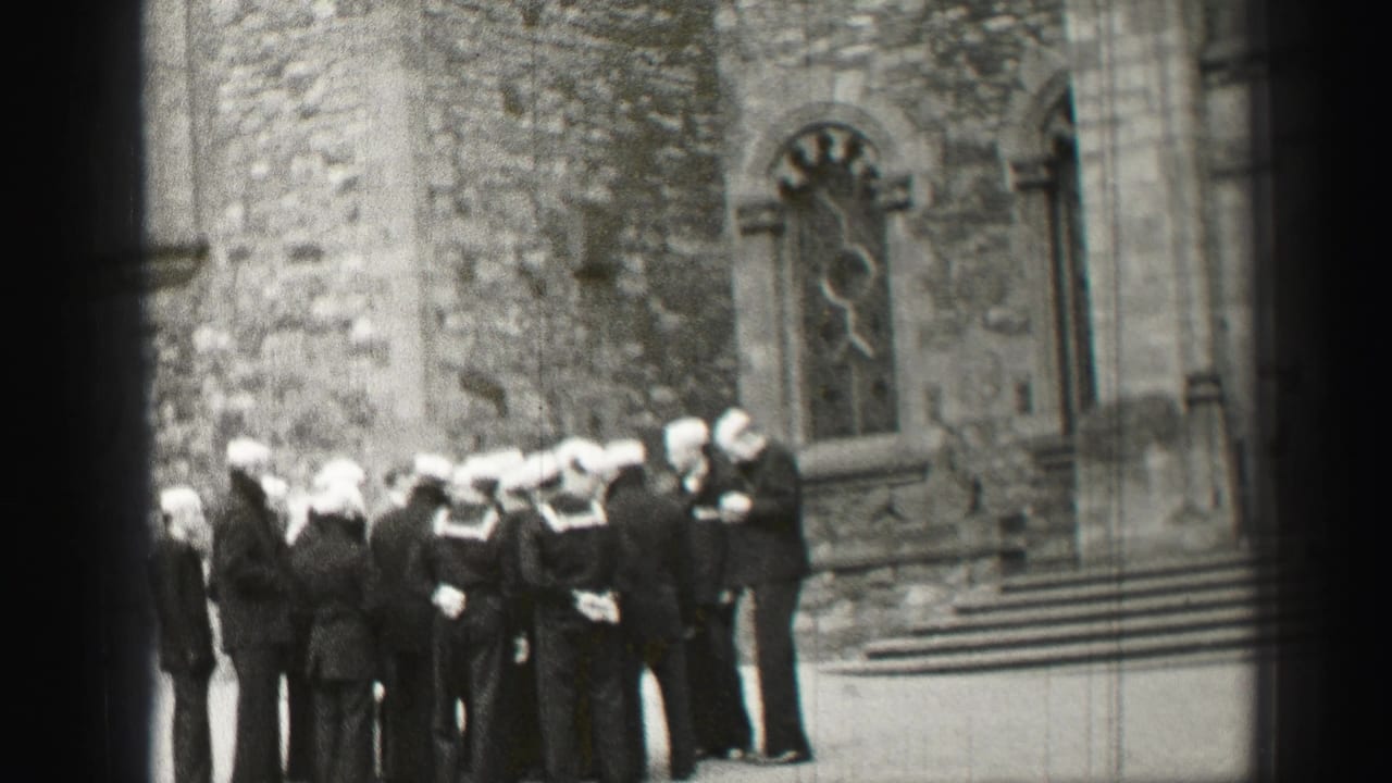 A cluster of sailors stands beside a stone church wall and arched window.