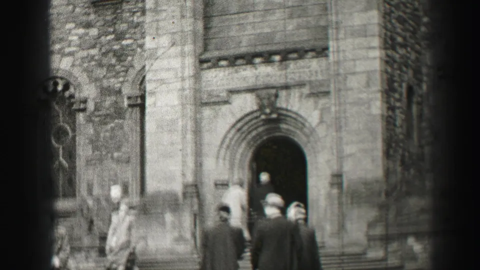 1952 Edinburgh home-movie frame showing adults in winter coats near a stone church entrance and arched doorway.