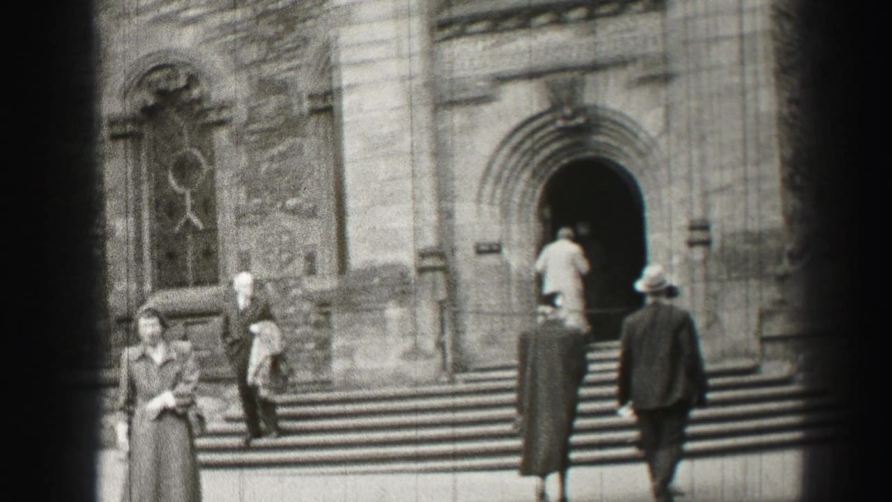 People climb broad stone steps toward an arched church entrance.