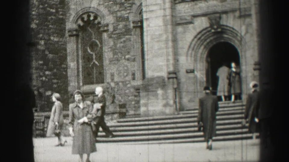 1952 Edinburgh church exterior with a woman in a long coat near the foreground and others walking toward the entrance.