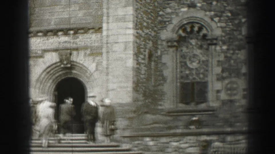 Adults enter or stand near the arched entrance of a historic stone building in the 1952 Edinburgh metadata clip.