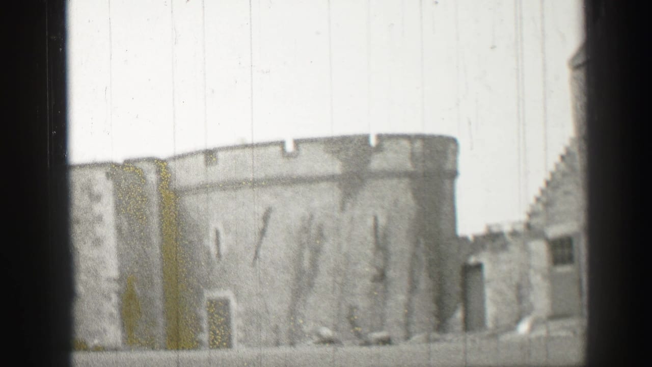 1952 8mm view of a stone castle tower and battlements in Edinburgh, framed by dark gate edges and film wear.