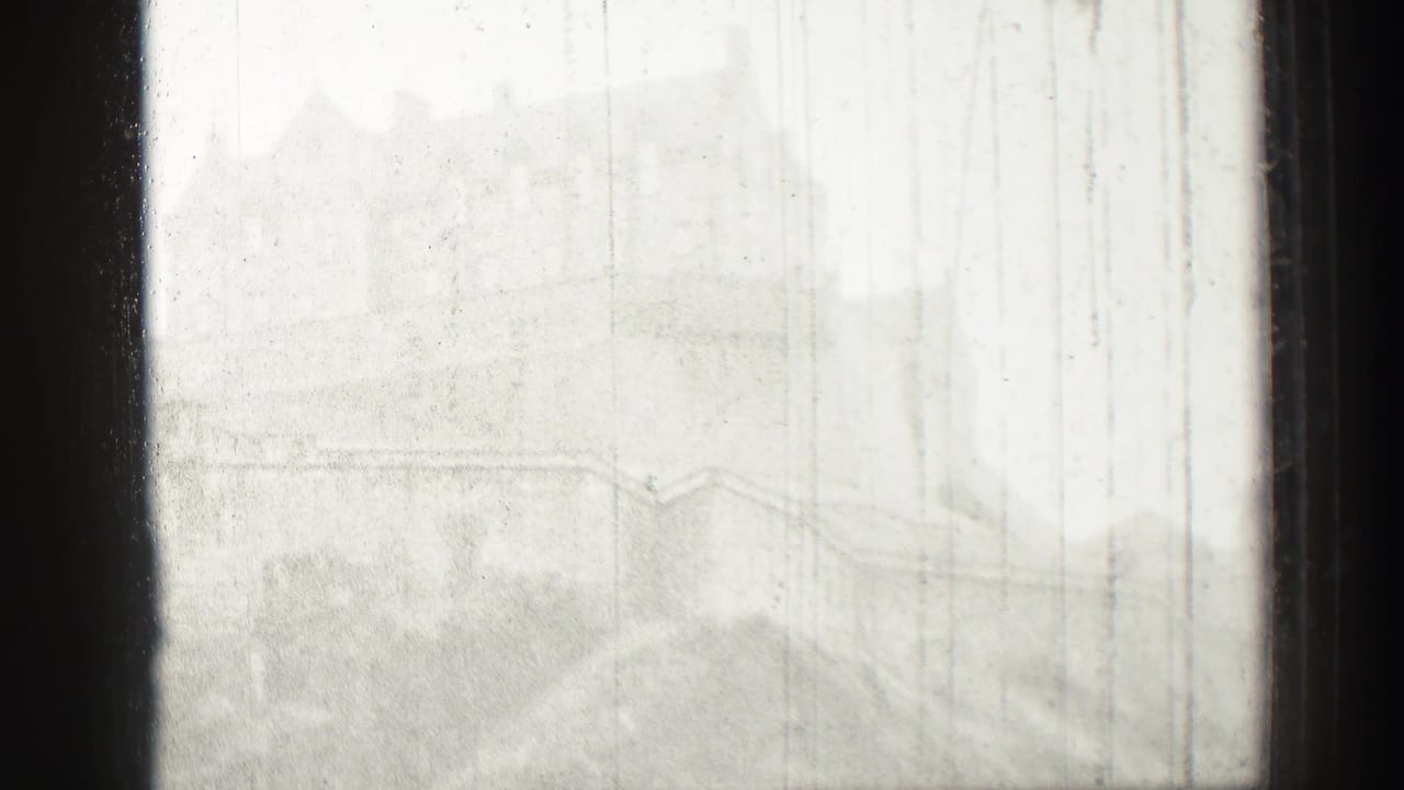 1952 Edinburgh, Scotland home-movie frame showing a distant castle and hillside softened by haze behind dark window mullions.