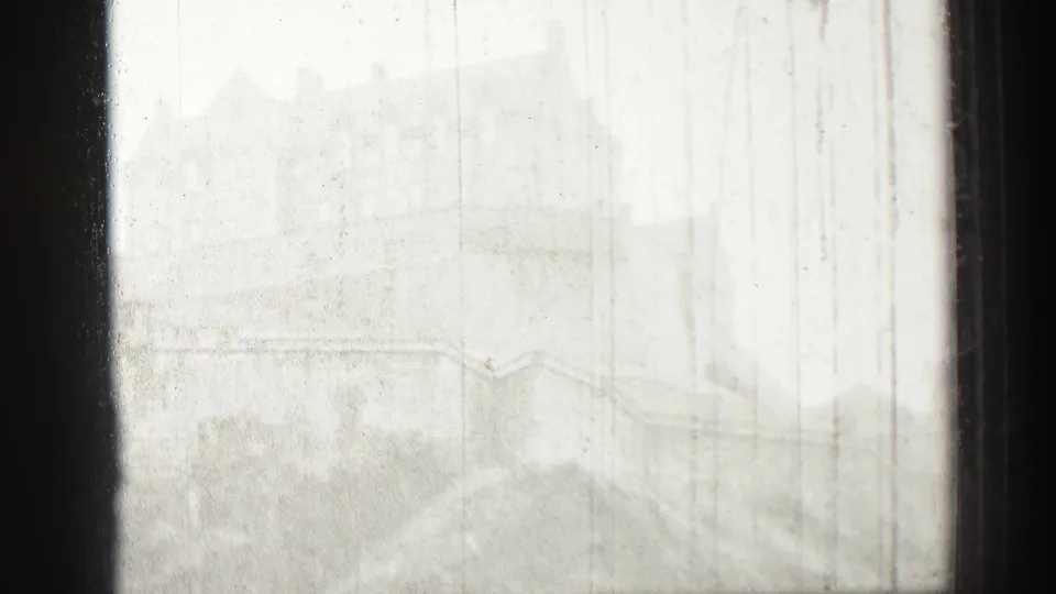 1952 Edinburgh, Scotland home-movie frame showing a distant castle and hillside softened by haze behind dark window mullions.