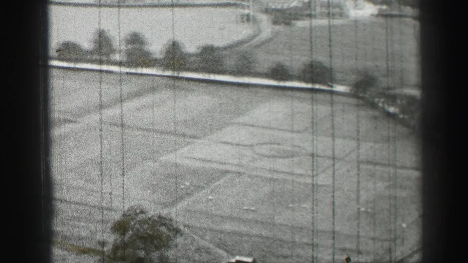 1952 Edinburgh home-movie view of a landscaped lawn with curved paths, faint circular markings, trees, and dark frame borders.