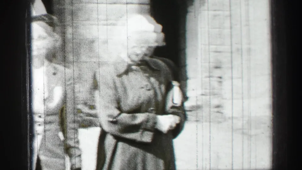 The women move closer to the camera in the supplied 1952 Scotland footage, one in a light hat and one in a darker coat.