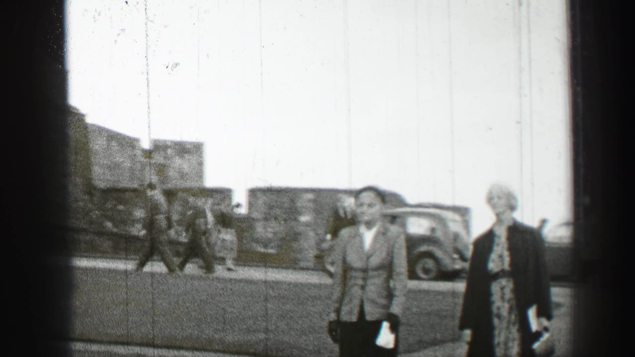 1952 Edinburgh street view with pedestrians in mid-century clothing walking near parked cars and stone buildings.