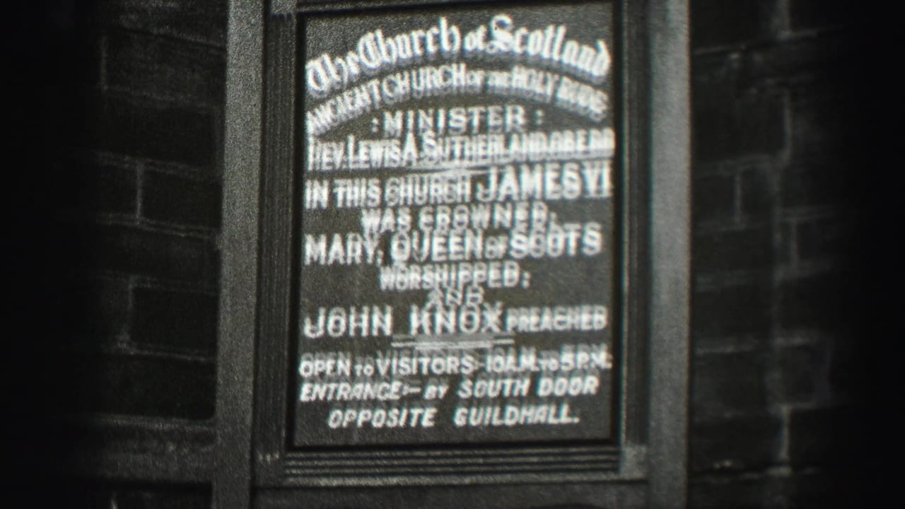 1952 Scotland home-movie frame showing a Church of Scotland historical sign on a dark exterior wall.