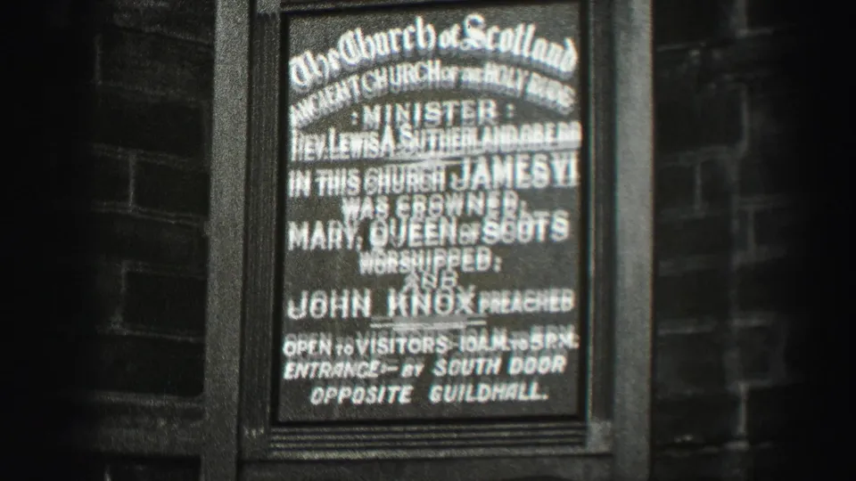 1952 Scotland home-movie frame showing a Church of Scotland historical sign on a dark exterior wall.