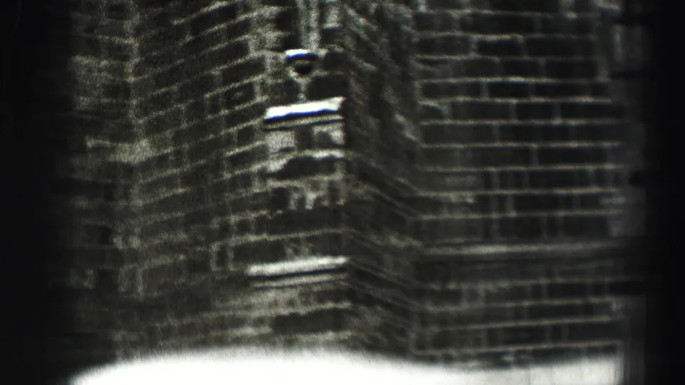 1952 8mm footage appears to show a close view of a Scottish brick building corner with soft focus, grain, and dark edge falloff.