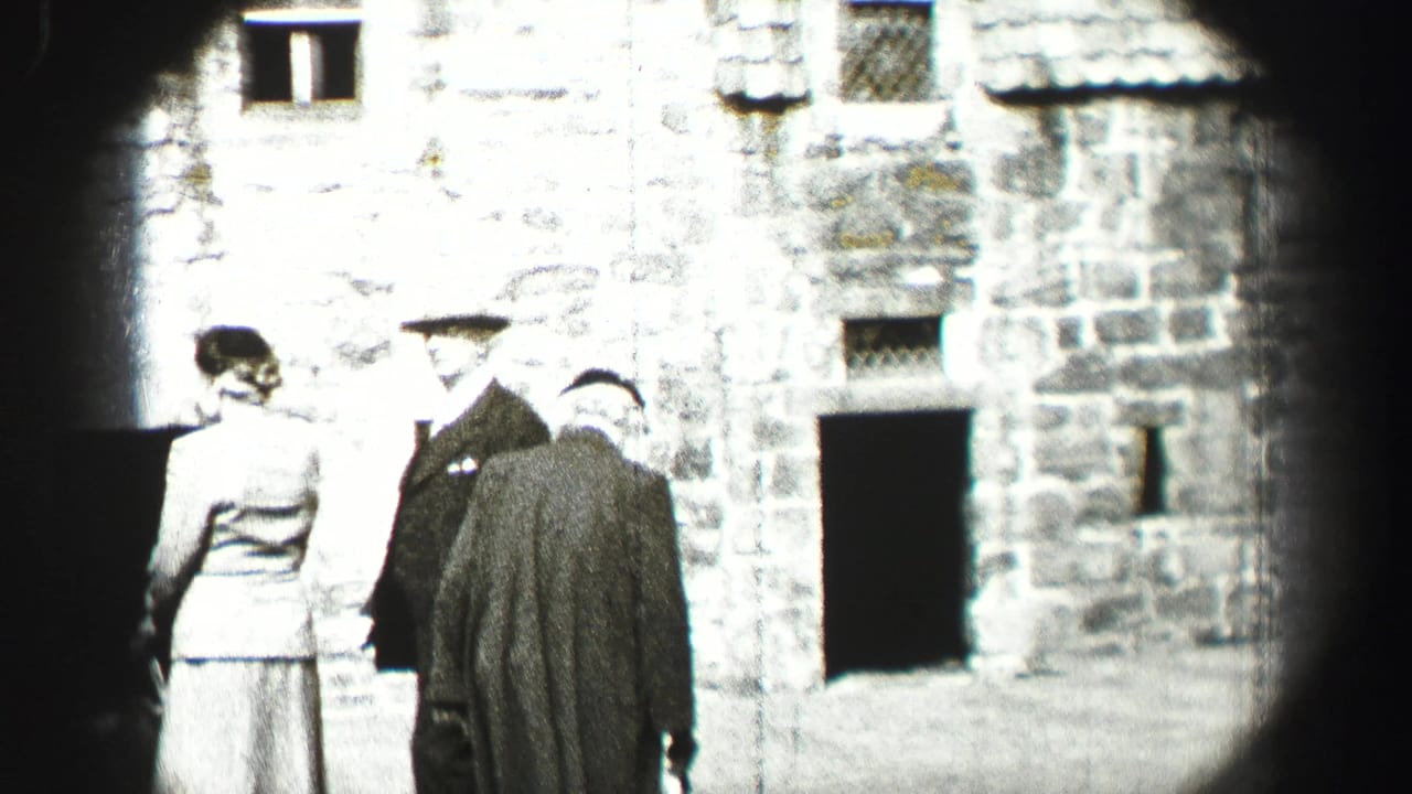 Two women and two men stand outside a weathered stone building.