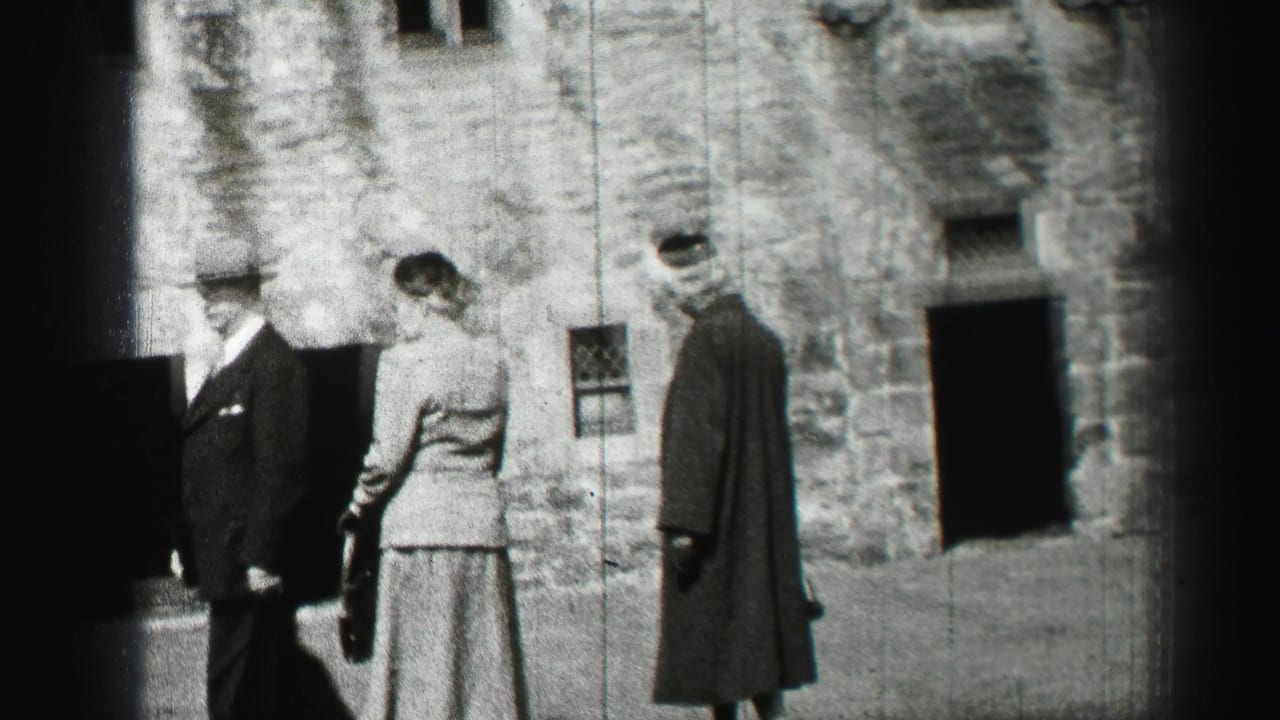 A suited man and two formally dressed women stand outside a stone building in the 1952 Edinburgh home-movie footage.